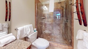 Une salle de bain dotée d’une douche à parois de verre, de toilettes et d’un lavabo avec un plan de travail en granit.