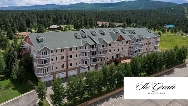 Un grand hôtel à plusieurs étages, doté d’une cour intérieure, entouré d’une forêt dense et de montagnes.