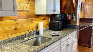 A kitchen with granite countertops, white cabinetry, and a wooden ceiling.
