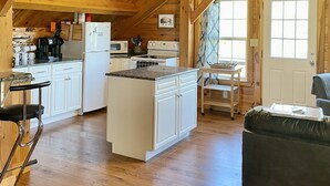 A spacious kitchen with wooden beams, a central island, and a ceiling fan.