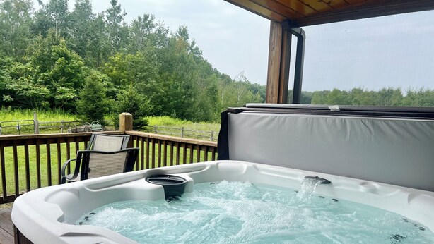 A hot tub on a wooden deck with a view of a forest.