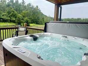 Un jacuzzi en una terraza de madera con vistas a un bosque.