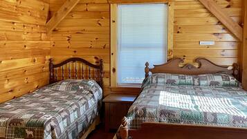 Un dormitorio tipo cabaña con dos camas de madera, una ventana con persianas y techo de madera.