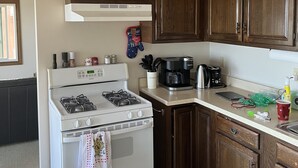 Eine Küche mit einem weißen Herd, Holzschränken, einer Kaffeemaschine und einer Hundeschüssel.