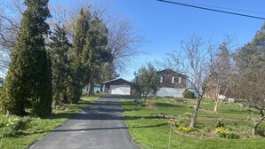 Ein Weg führt zu einem Haus mit Garage, umgeben von Bäumen und einem Rasen.