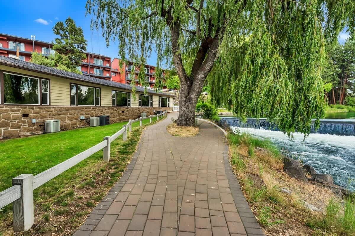 Ein Weg führt zu einem Gebäude mit einer Steinauffassung, einer Weeping-Willow-Baum und einem Fluss.