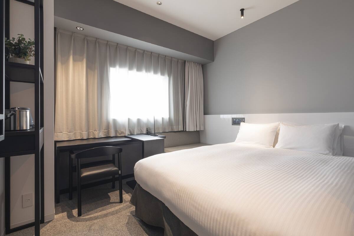 Une chambre d’hôtel moderne, dotée d’un grand lit, d’un bureau et d’une chaise.