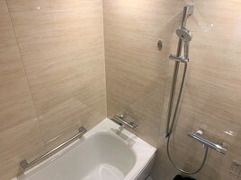A modern bathroom with a bathtub, a shower with a handheld showerhead, and a glass-enclosed shower stall.