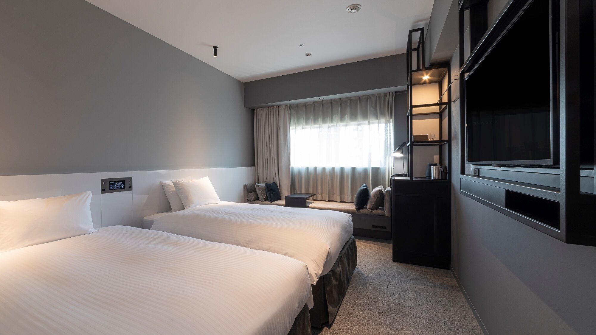 Een hotelkamer met twee bedden, een televisie, een bureau en een raam met gordijnen.