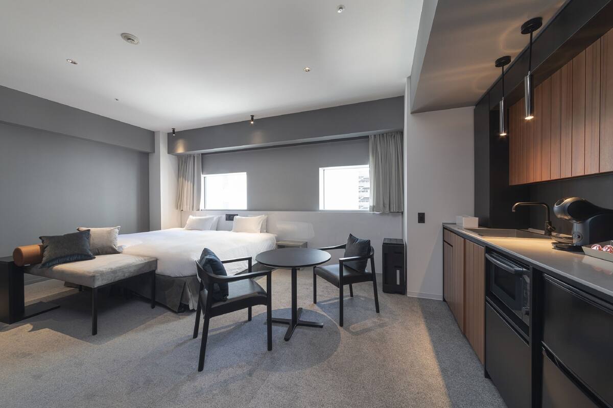 Une chambre d’hôtel moderne équipée d’un lit, d’un coin salon et d’une kitchenette.
