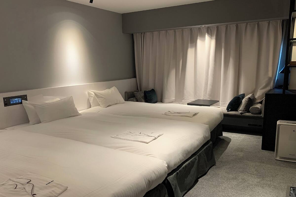 Une chambre d’hôtel avec deux lits, un bureau, une chaise et une petite table.