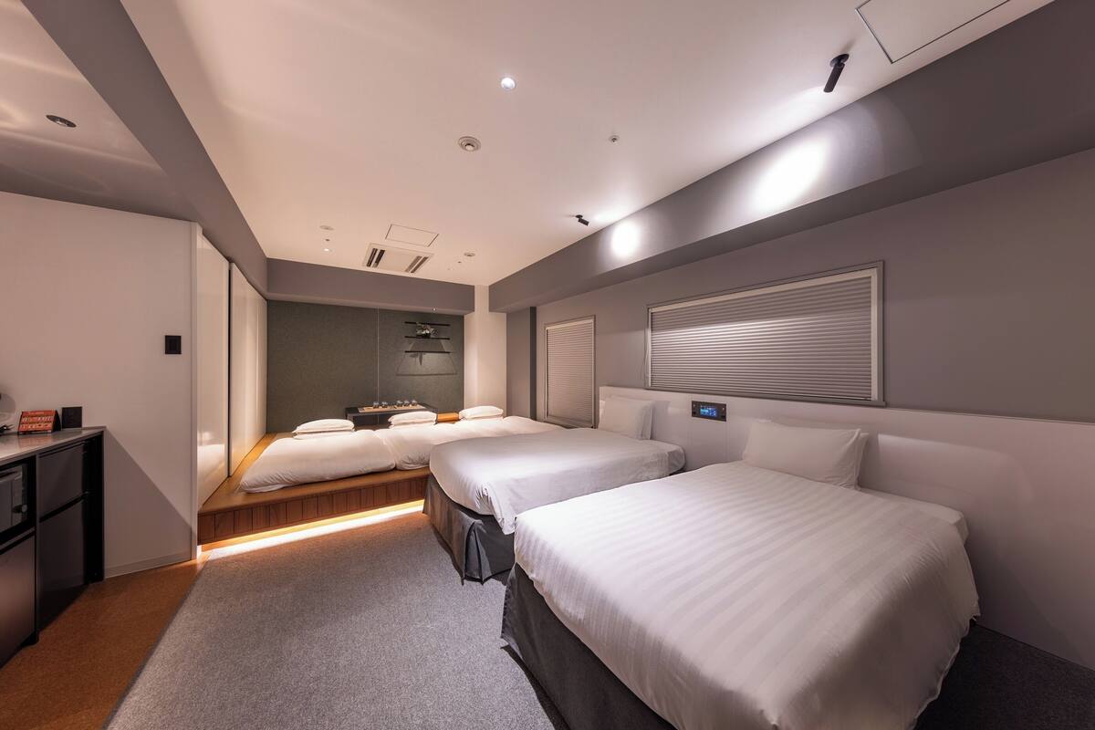 Une chambre d’hôtel avec deux lits, un bureau et une salle de bain avec douche.