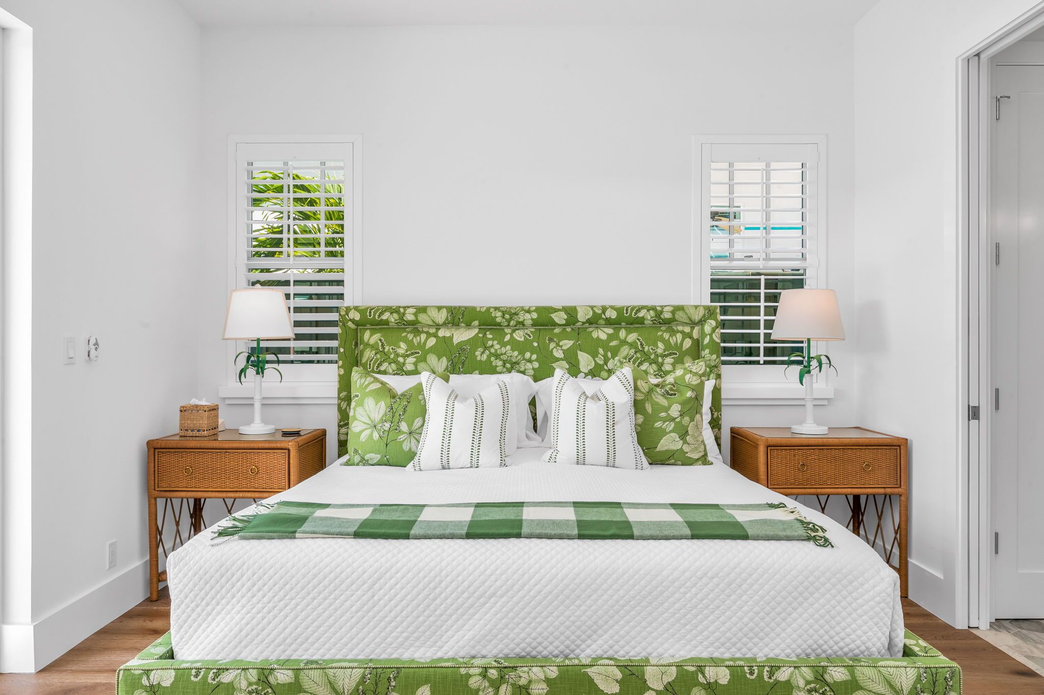 A neatly arranged bedroom with a large bed, two bedside tables, and a window with blinds.