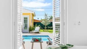 Una habitación con vista a una piscina, una puerta y una pequeña mesa con una botella y un vaso.