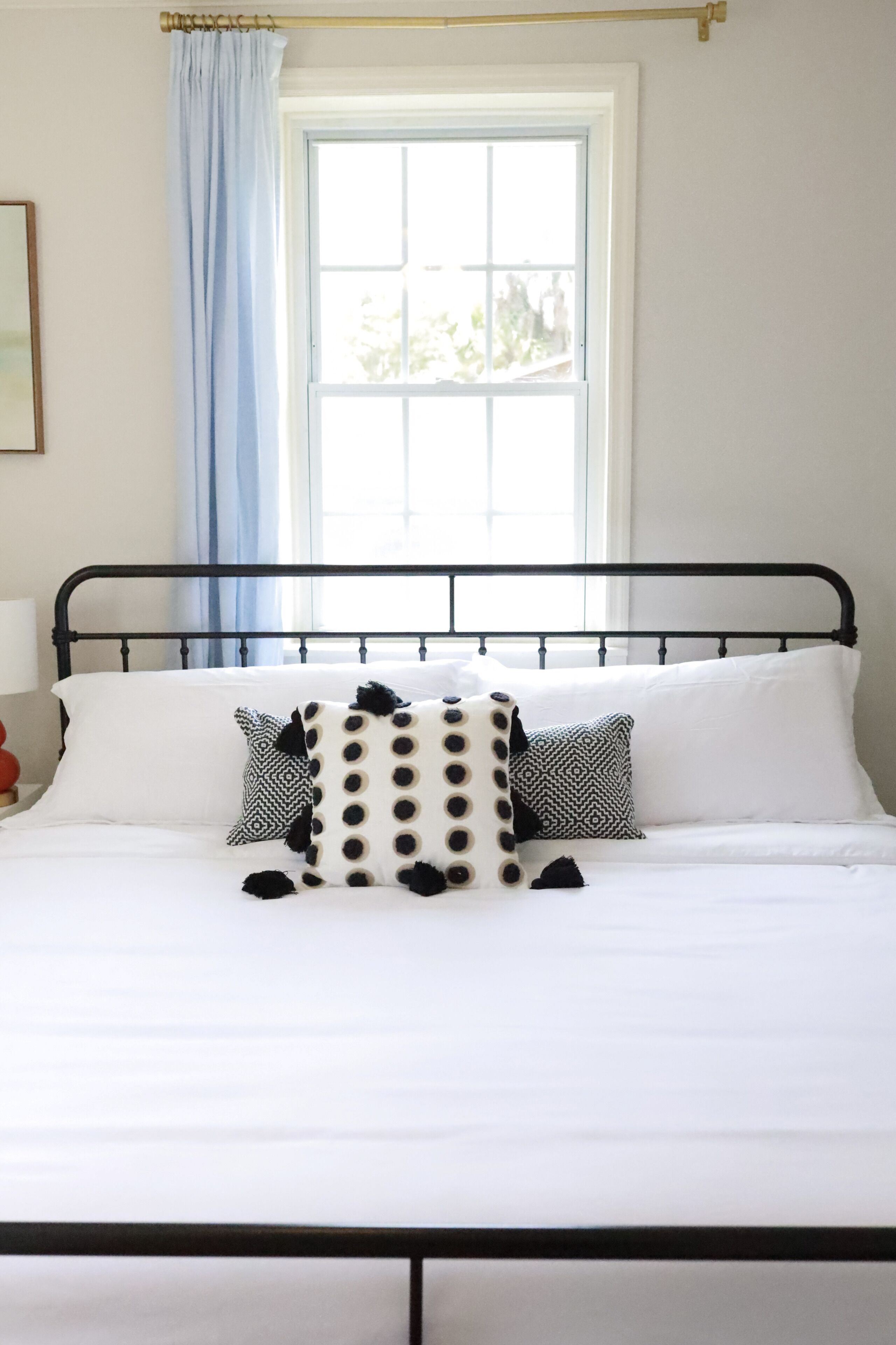 A bed with a black metal frame, white bedding, and patterned pillows.
