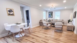 Amplia sala de estar con comedor, piso de madera y un gran sofá seccional.