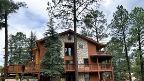 A two-story lodge with a stone facade, wooden balconies, and a surrounding forest. - Xterra Championship Availability, Game Room, Sleeps 10 and Pet Friendly! (Ruidoso)