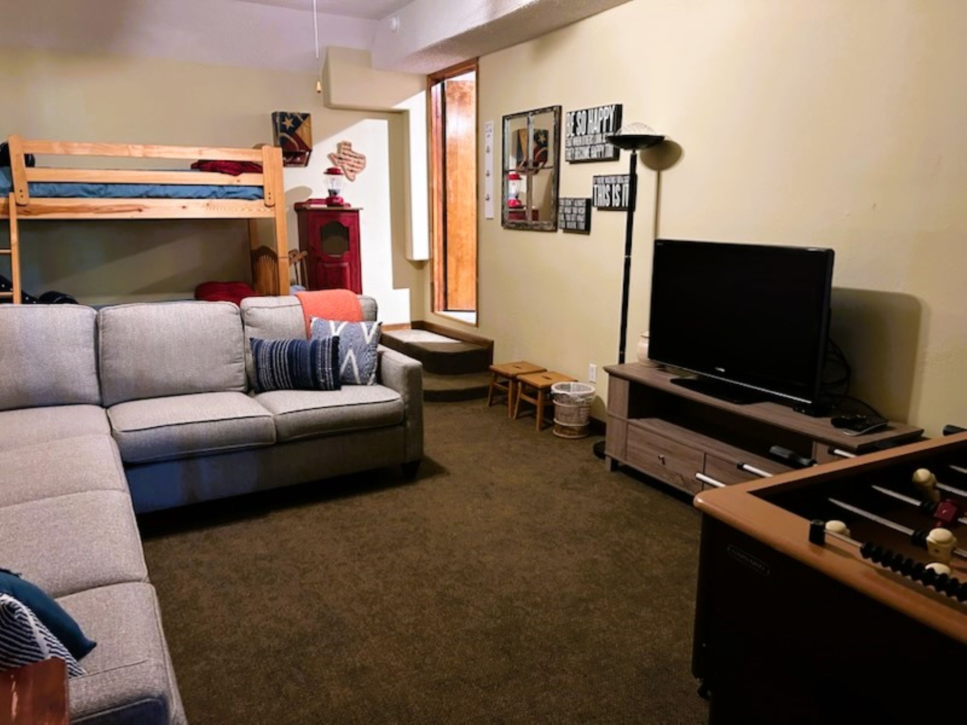 A compact living space with a sofa, a TV, a futsal table, and a bunk bed.
