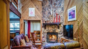 A cozy living room with a stone fireplace, leather furniture, and a television. - Xterra Championship Availability, Game Room, Sleeps 10 and Pet Friendly! (Ruidoso)