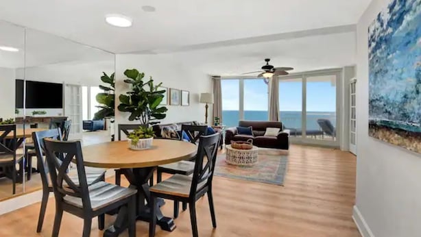 Una sala de estar moderna con comedor, ventanas amplias y vista al océano.