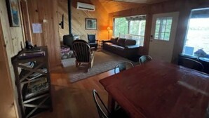 Un intérieur de chalet chaleureux, avec un revêtement mural en bois, un canapé, une table à manger et une cheminée.