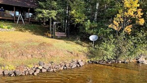 Une cabane dotée d’une véranda donnant sur un ruisseau aux eaux limpides.