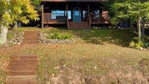 Un chalet rustique doté d’un porche en bois et d’un chemin en pierre menant à l’entrée.