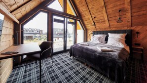 Une chambre avec une grande fenêtre, un lit, un bureau et une chaise.
