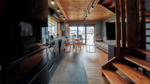 Une cuisine moderne dotée d’un îlot central, de planchers en bois et d’un coin repas avec une table et des chaises.