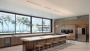 A modern kitchen with a large island, bar stools, and a view of the ocean. - Saba Estate Luxury Villa Bali (Blahbatuh)