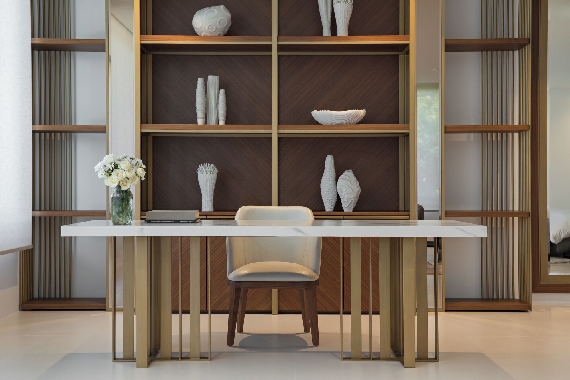 A modern interior with a white table, a chair, and a wooden bookshelf with decorative items.