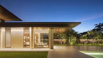 Une maison moderne avec une façade en verre, un toit plat et une pelouse bien entretenue.