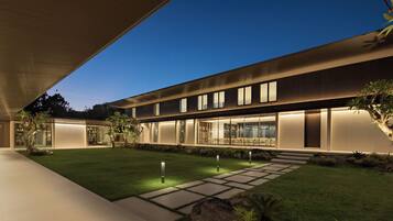 Una casa moderna con un patio amplio, un césped cuidado y un comedor con grandes ventanales.