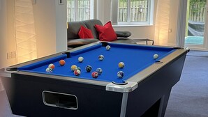 A pool table with balls in a room with a sofa and a window.