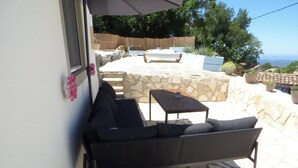 An outdoor patio with a sofa, a small table, and a stone wall. - Lovely Studio in Strinilas with its own pool (Strinilas)