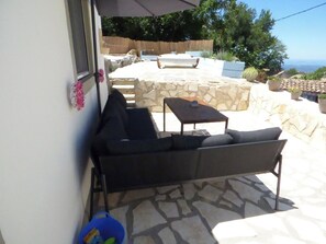 An outdoor patio with a sofa, a small table, and a stone wall. - Lovely Studio in Strinilas with its own pool (Strinilas)