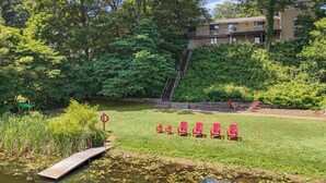 A grassy area with a pond, red chairs, and a wooden dock. - Available Sept 7-10 & 13-17- Private Mini Resort w Indoor Pool & Sauna (West Olive)