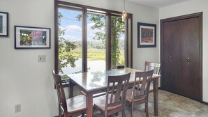 A dining area with a glass-top table and wooden chairs, large windows with a view of greenery and a lake, and framed pictures on the walls. - Available Sept 7-10 & 13-17- Private Mini Resort w Indoor Pool & Sauna (West Olive)