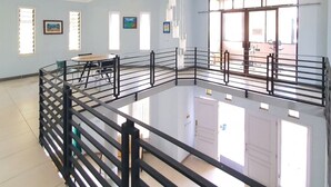 Una habitación amplia con techo alto, ventanas grandes y barandilla de vidrio que da a un nivel inferior.