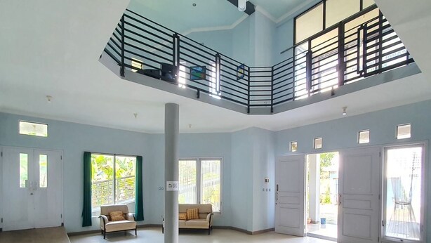Amplia sala de estar con techo alto, balcón y ventanas grandes que dejan entrar luz natural.