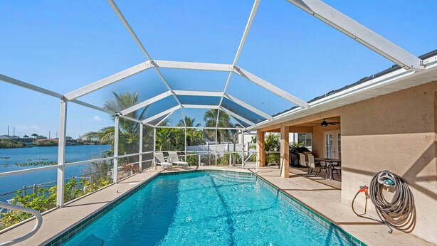 Una piscina techada con vistas al agua y palmeras.