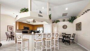 Una cocina moderna con barra, armarios de madera y un espacio comedor con sillas.