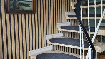 Una escalera en espiral con un muro de madera y dos cuadros enmarcados.