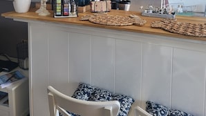 Eine Küche mit Barbereich, einer hängenden Lampenleuchte und einem Wandschild mit der Aufschrift 'Coffee'.