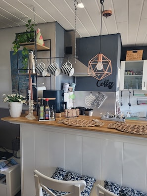 Uma cozinha com área de bar, luminária pendente e um letreiro na parede que diz 'Coffee'.