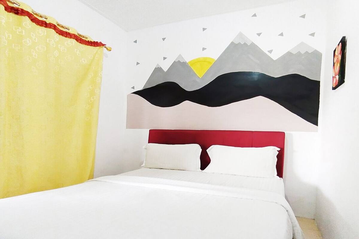 A bed with white bedding, a red headboard, and a yellow curtain.