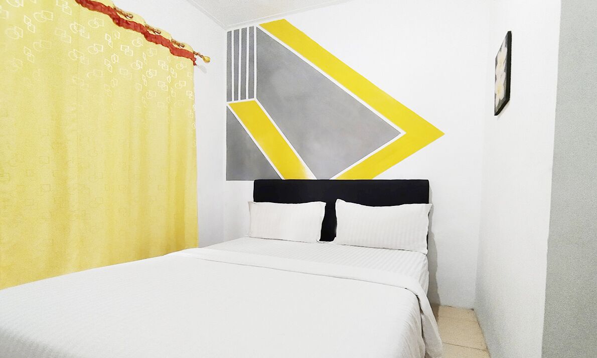 A bedroom with a bed, a geometric wall decoration, and a curtain.