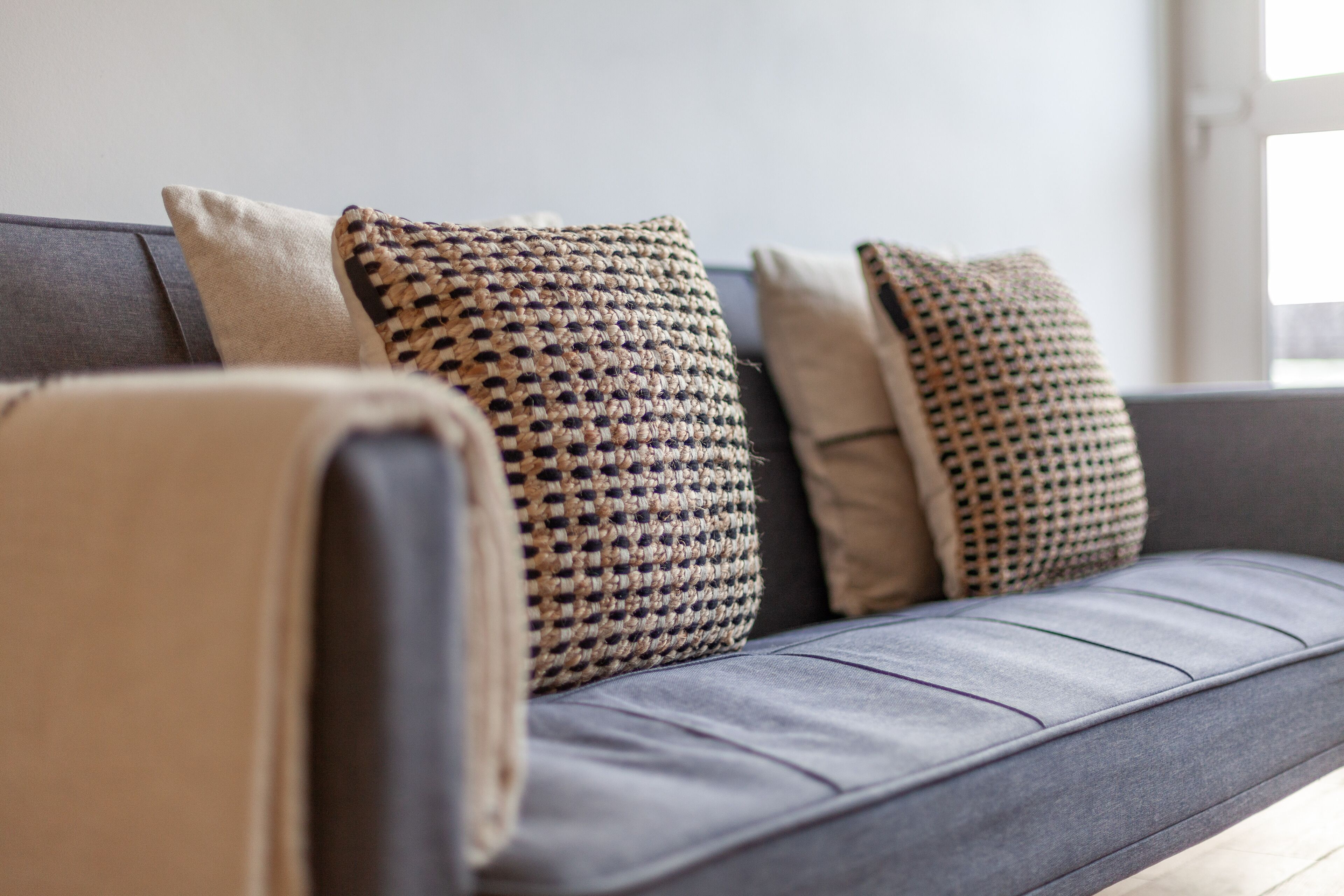 A grey sofa with three patterned cushions and a plain cushion.