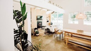 Un salón amplio con un ventanal grande, una chimenea y una mesa de comedor con bancos.