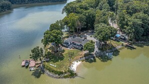 Vue aérienne d’une propriété au bord du lac, avec une maison, un quai et des bateaux.